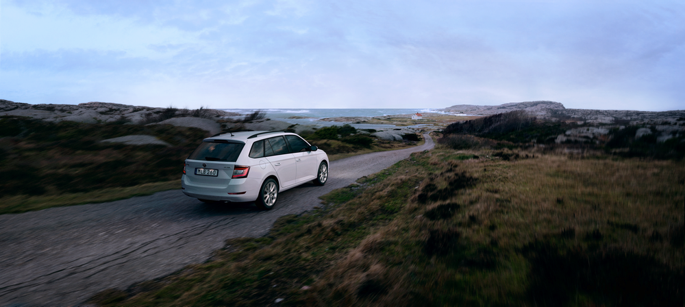 Skoda som åker längs en väg vid havet bland klipporna