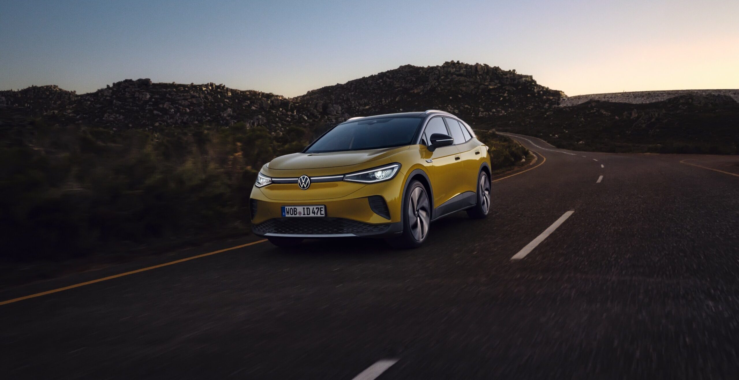 Gul Volkswagen som kör på en väg i solnedgång